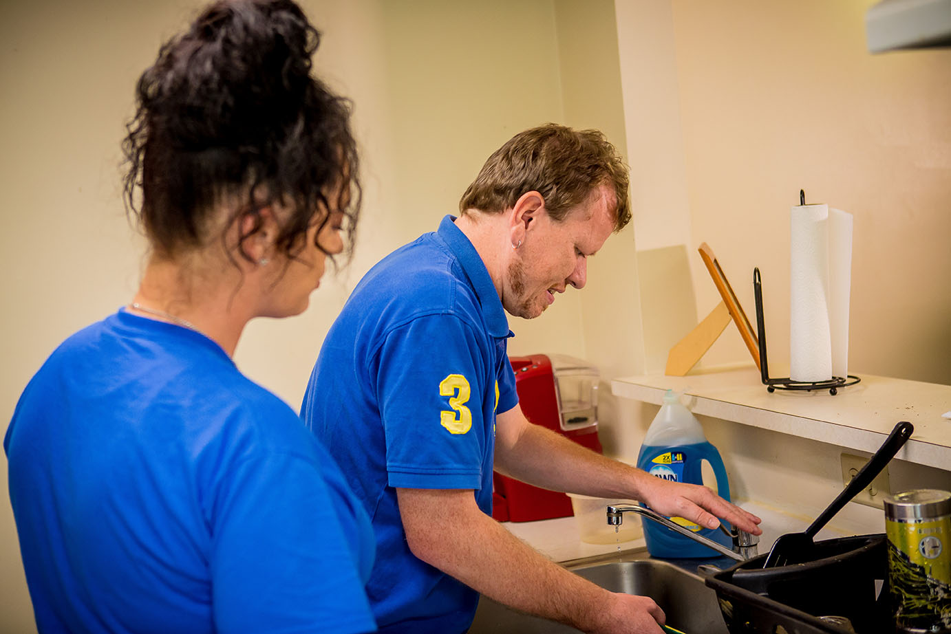 Man doing dishes with in home care professional behind him