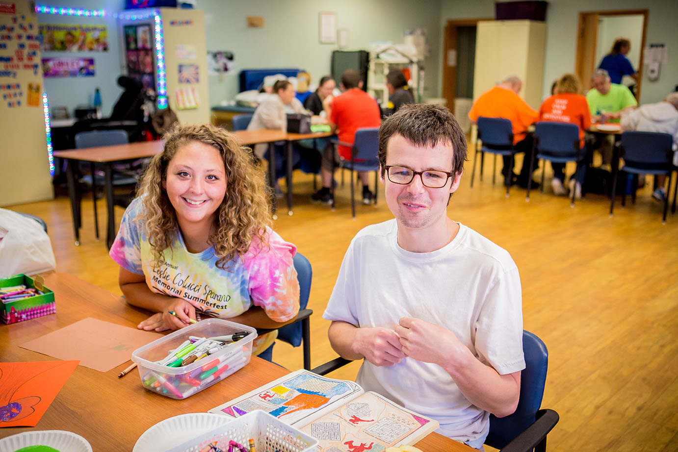 man and woman sitting at table smiling doing crafts